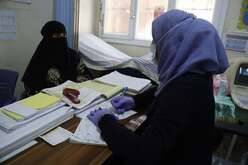 Two women sit across from each other at a table in an office.