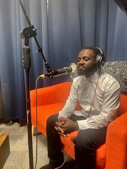 man sitting on couch with headphones on and microphone 