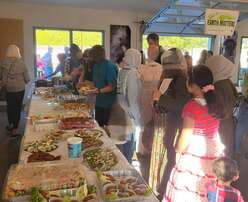 People fill plates from buffet table from a community potluck to welcome newcomers