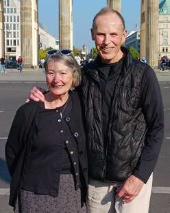 Fred and Adele smile standing with arms around each other during travels