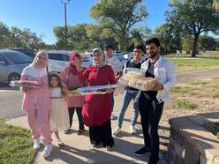Newcomer family holding trays of food for community potluck