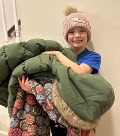 An image of IRC volunteer Lindsay's daughter gathering coats.