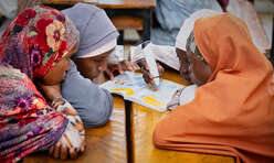 Fyra flickor i Nigeria sitter vid ett bord och studerar.