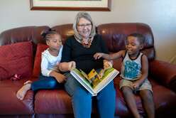 IRC worker reading with children on the couch