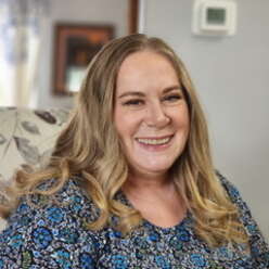 Jackie smiles sitting in her home