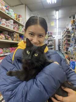Molly Murch volunteer tutor smiles posing with a black cat in a store aisle 