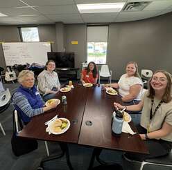 Five female volunteers sit at a table enjoying lunch at the IRC's Volunteer Appreciation event.