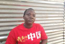 Frau im rotem T-Shirt während Interview vor Wellblechwand.