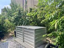 The compost bin beside the pomegranate tree
