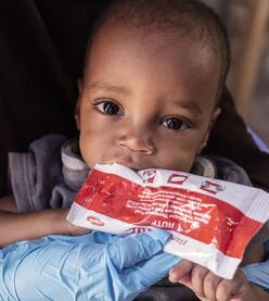 Amina’s son eats Plumpy’Nut, a protein-rich paste used to treat malnutrition.