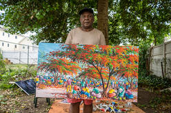 Artist Muyambo Marcel Chishimba holding one of his paintings.