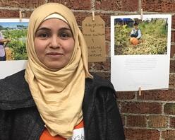 Aysha, New Roots gardener from Syria, poses with a picture she took of her son.