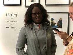 A woman looking at her pone, and another looking at the camera with hands in her pocket.