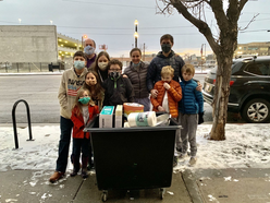 A large family poses in front of the items they donated to the IRC for light one candle