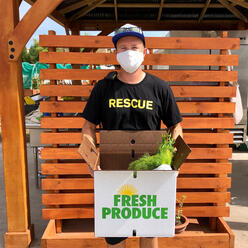 Isaac, an IRC staff member, holds a Fresh Produce Box.