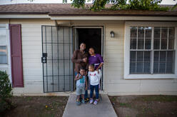 Congolese refugees Robert and Esther pose for a photo with their two young children at the front  door of their home in Phoenix.