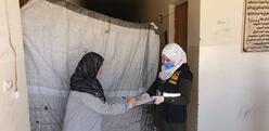 An IRC worker in a face mask to protect against COVID-19 give emergency cash to a Syrian refugee woman in Bekaa, Lebanon.
