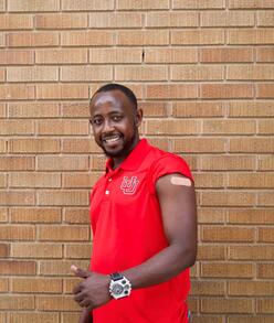 Mahamat smiles for the camera and holds a "thumbs up" with his left arm, showing off the vaccination bandage.