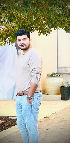 Ahmad stands outside with his hands in his pockets looking at the camera