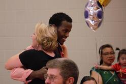 Refugee and community member hug during World Refugee Day celebration