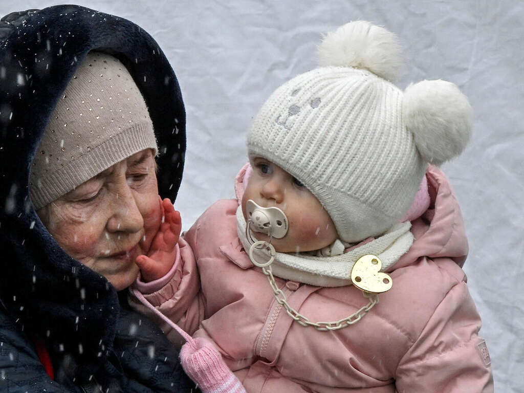 Vintern i Ukraina: En kvinna håller i hennes barnbarn under ett snöfall vid gränsen mellan Polen och Ukraina.