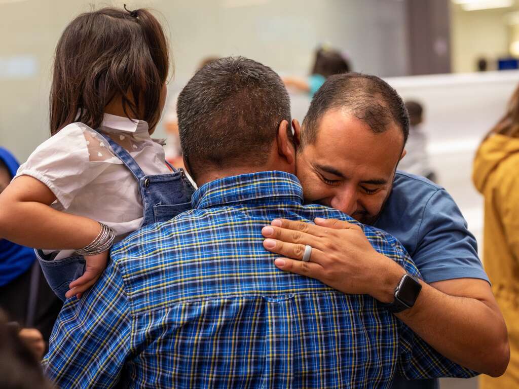Pedro Moncada, an IRC immigration legal representative, embraces Mr. Husseini after his family was reunited.