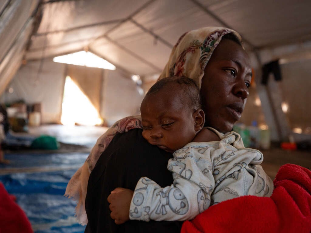 Muhammad Ali tröstar sitt barn på fyra månader i Kiryandongo, Uganda. De flydde från Sudan några månader efter att kriget bröt ut. 