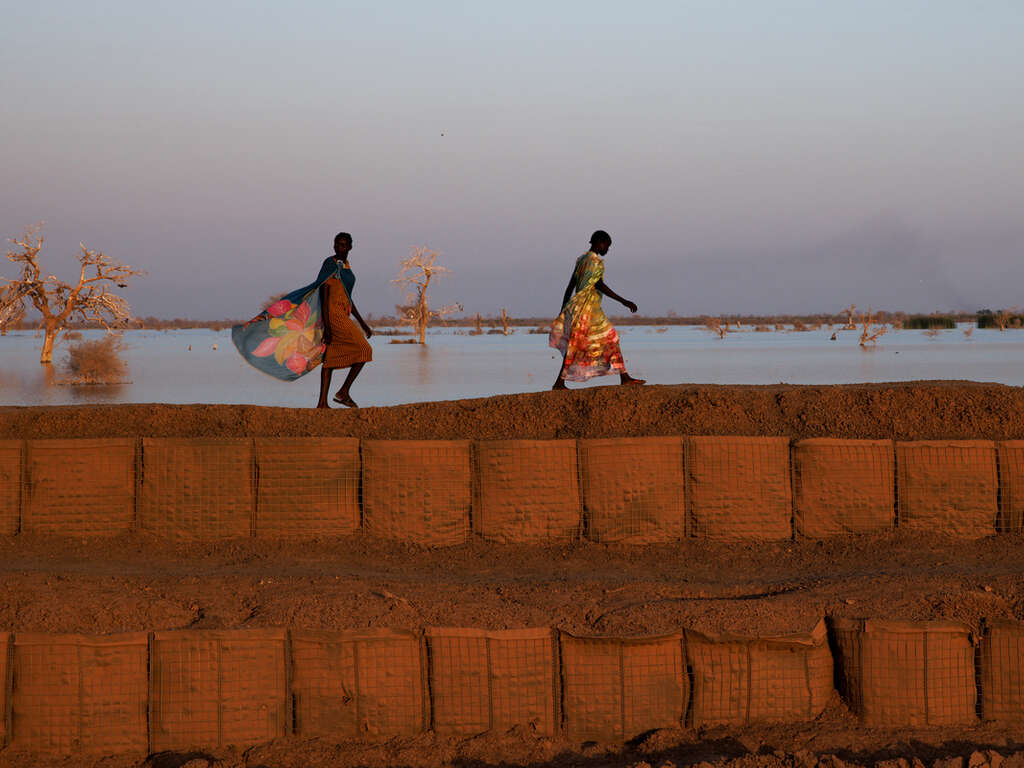 Två kvinnor går på en mur i Sydsudan.