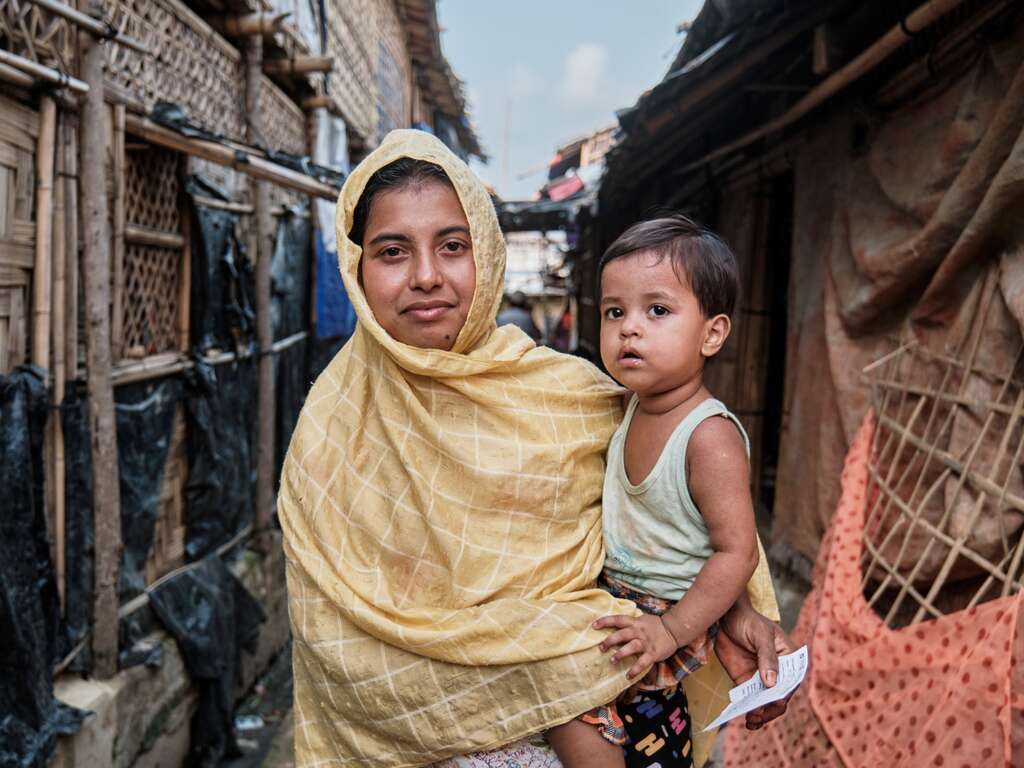 A Rohingya refugee and mother holds her child in her arms.
