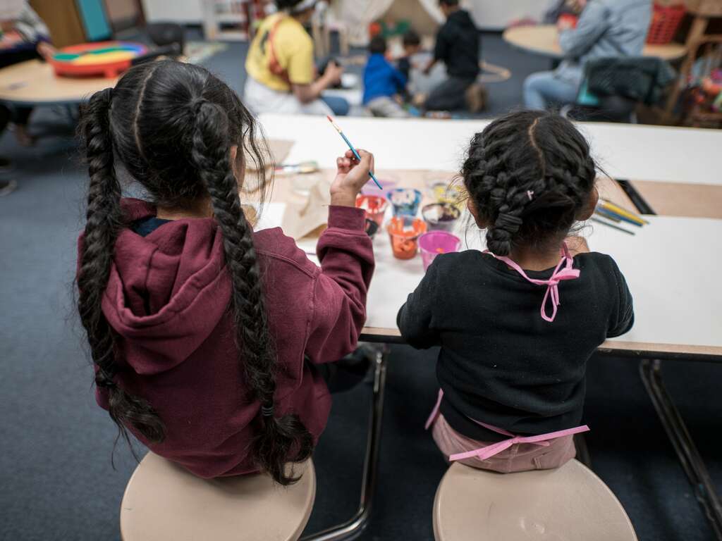 Two young girls sit next to each and other and draw at an IRC safe space.