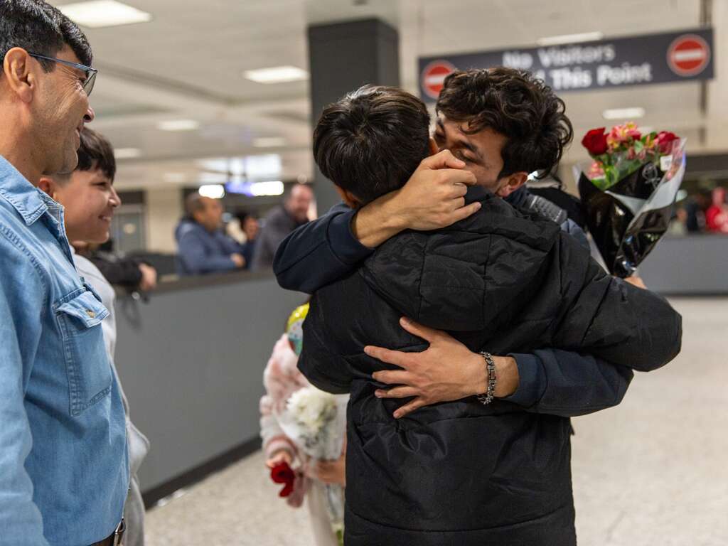 Two brothers embrace after they are reunified at an airport in the US.
