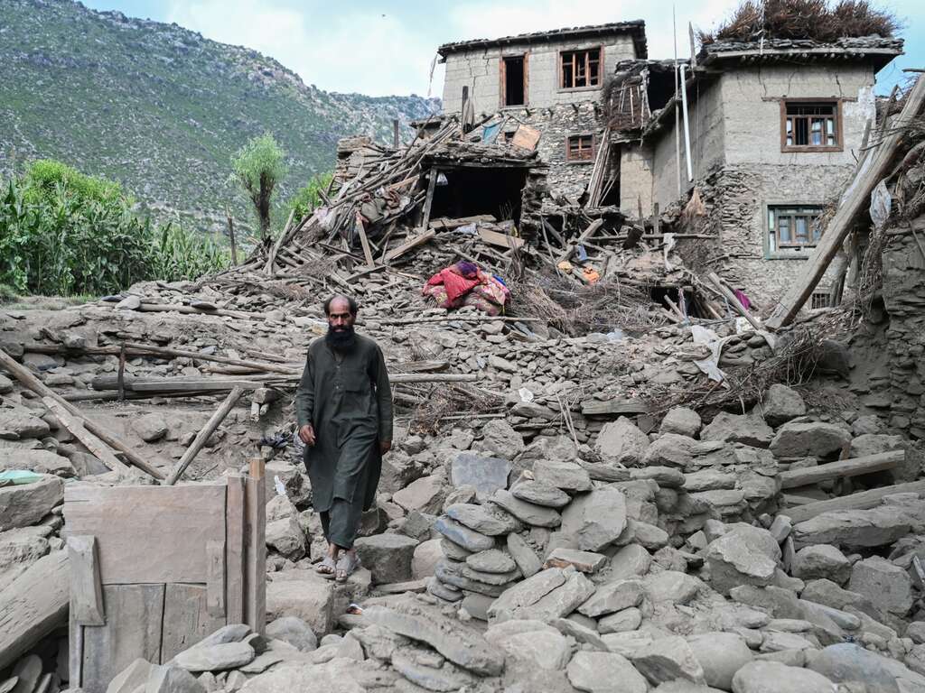 An Afghan man walks through the ruins of his home which was recently destroyed by a severe earthquake.