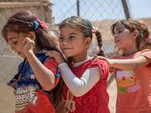 Drei Mädchen halten sich an den Schultern.