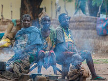 Drei Frauen sitzen an einer Feuerstelle in einem Flüchtlingslager.