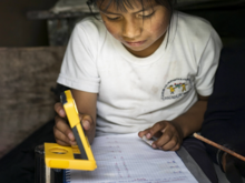 A girl in Latin America using a WakaWaka solar light to do her homework.
