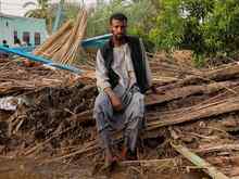 한 남성이 폐허가된 집 앞에 앉아 있습니다.