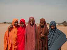 Five women look at the camera, smiling