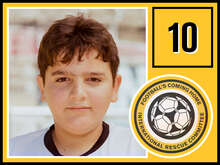 Ein Junge mit kurzem, dunklem Haar trägt ein weißes T-Shirt mit schwarzem Kragen und blickt ruhig in die Kamera.