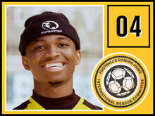 Ein junger Mann mit einer schwarzen Mütze mit der Aufschrift "buntkicktgut" lächelt breit in die Kamera.