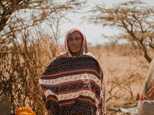 한 여성이 임시 거처 앞에서 앉아 있습니다.