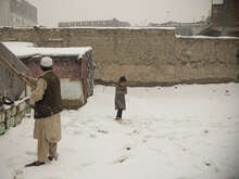 한 소녀가 눈덮인 텐트 앞에서 외투도 없이 추위에 몸을 안고 있습니다.