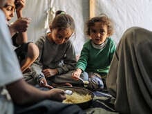 En familj i Gaza sitter i sitt tält och äter mat.