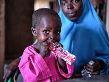 En pojke i Nigeria håller i en nötkrämspåse, han får vård mot undernäring av RESCUE.