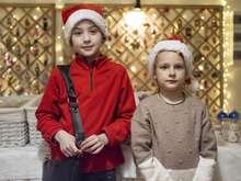두 어린이가 산타클로스 모자를 쓰고 나란히 서서 카메라를 바라보고 있습니다.