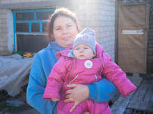 한 우크라이나 여성이 아기를 안고 카메라를 바라보고 있습니다