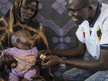 국제구조위원회 의사가 엄마 품에 안긴 어린이의 영양실조 징후를 확인하고 있습니다.