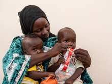 한 엄마가 아기를 안고 영양실조 치료식을 먹이고 있습니다.