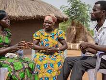 Community members talking together in a rural village setting.