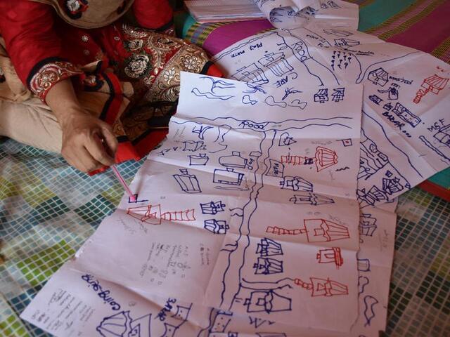 drawn maps on a floor, a finger pointing on one of them