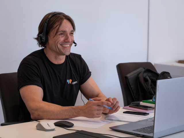 Roman sits smiling at his computer while on a call